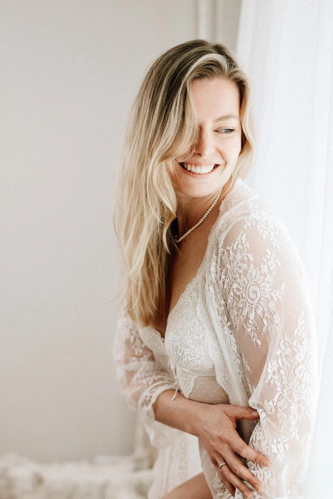 Frau im Spitzenkimono lacht herzlich zur Seite, Boudoirfotografie Julia Aßmann